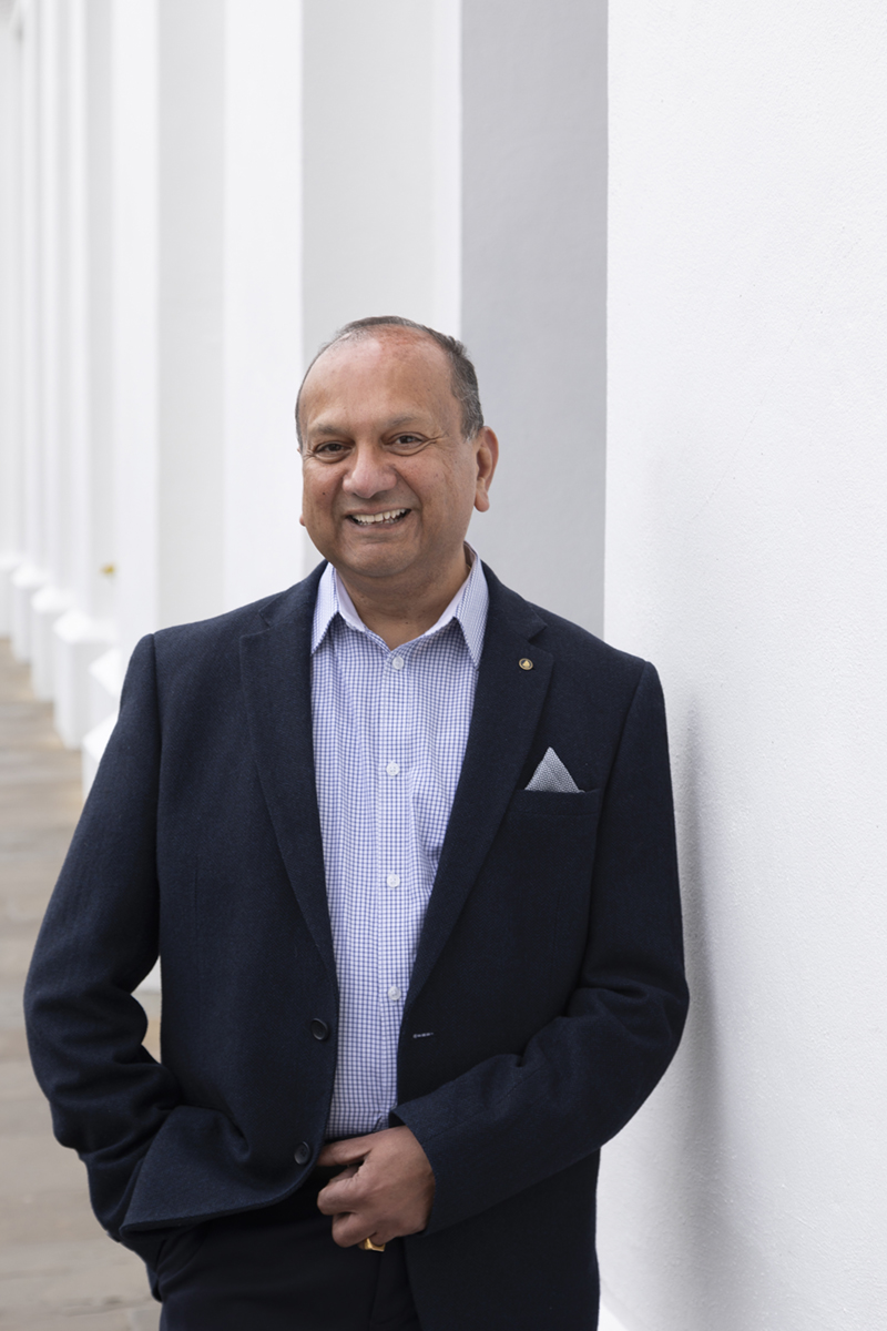 A man leaning against a wall for a headshot photograph.