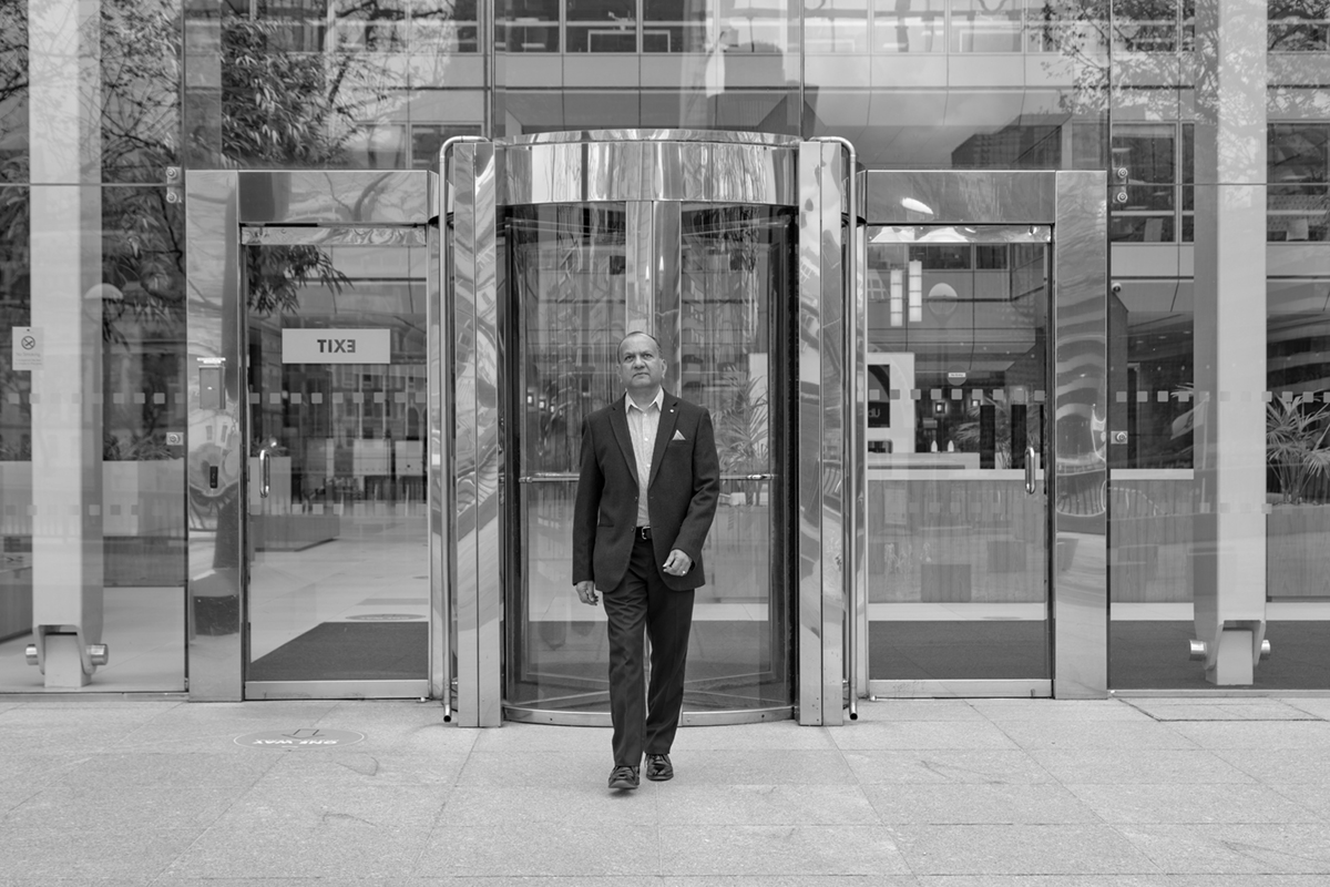 A man walking out of an office building in Black & White.