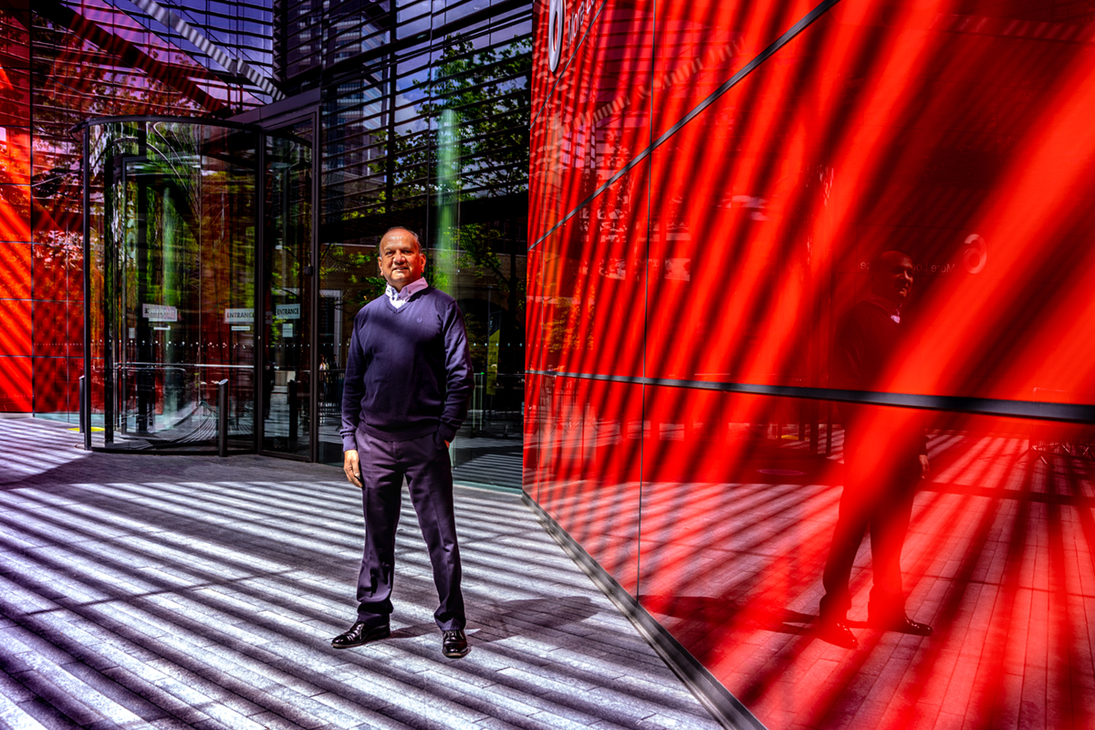 A man standing in front of a building with large red tiues.