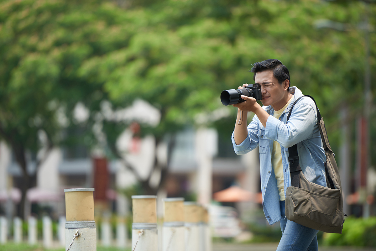 A young photographer taking photographs in a city park